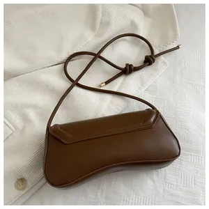 Close-up of a vintage brown leather crescent bag with unique knotted rope strap detail