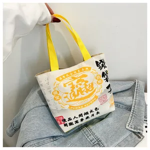 Detailed view of cream canvas bucket bag with yellow handle and Chinese calligraphy art