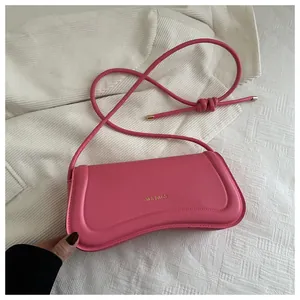 Detail of rose pink faux leather baguette bag with gold logo and knotted strap