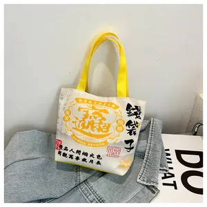Close-up of Chinese style canvas bucket bag with yellow handles on denim jacket