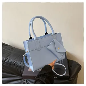 Close-up of light blue leather tote bag with matching envelope pouch and embossed logo