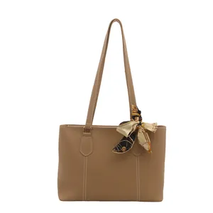 Minimalist khaki tote bag with contrast stitching and silk scarf accessory on the handle
