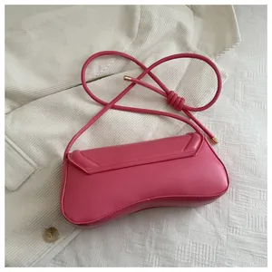Detail shot of a bright pink PU leather shoulder bag with gold metal tips on the strap