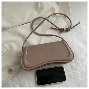 Size comparison of a beige leather shoulder bag next to a smartphone for scale