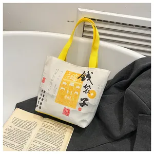 Detail of white canvas tote bag with yellow straps and Chinese folk art illustration
