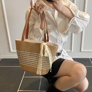 Handmade striped straw tote bag with brown leather handles and a white lace ribbon accessory