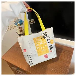 Close-up of cream canvas tote bag with yellow straps and Chinese calligraphy print