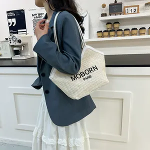 Bolso tote de paja con ribete de cuero blanco y bordado MOBORN PARIS en el modelo