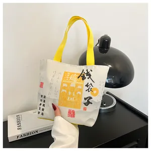 Detail of canvas bucket bag featuring Chinese calligraphy and yellow nylon handles