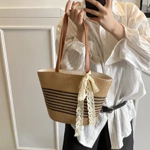 Woven straw tote bag with brown stripes and white lace bow accessory for vacation