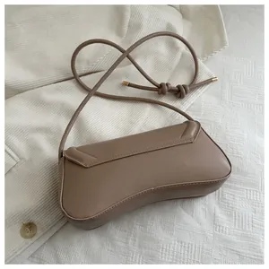 Detail view of mocha brown leather crescent bag with thin strap and gold metal hardware