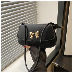 Gros plan du sac bandoulière noir avec une boucle dorée en forme de nœud élégant