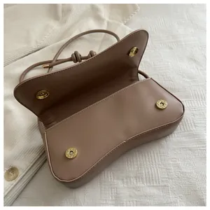 Detail of tan leather crossbody bag featuring dual magnetic closures and interior space