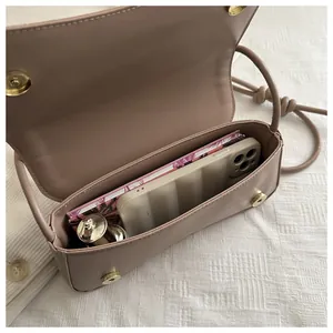 Top view of compact pink leather shoulder bag interior with phone and lipstick