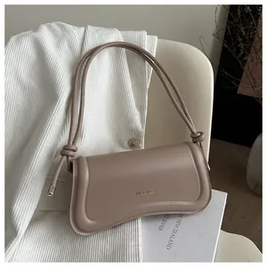 Detail of minimalist beige curved shoulder bag with knot strap and brand logo