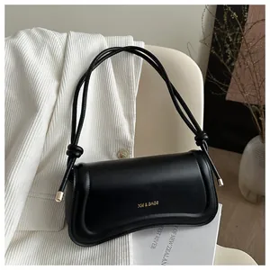 Close-up of black leather crossbody bag with gold XM & BAGS logo and tied strap detail
