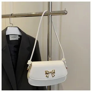 Détail du sac bandoulière en cuir blanc avec fermoir nœud doré et sangle à nœuds