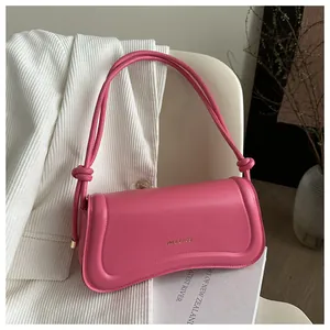 Detail of fuchsia matte faux leather shoulder bag with gold lettering and knot strap detail