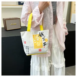Detail of canvas tote bag featuring traditional Chinese calligraphy and yellow handles