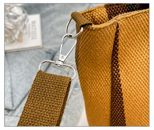 Detail of silver lobster clasp and thick woven shoulder strap on a striped canvas tote bag