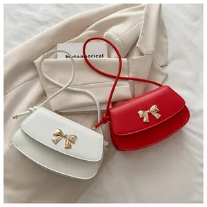 Vue détaillée de petits sacs bandoulière blancs et rouges avec boucles nœuds dorés