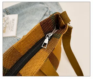 Detail of smooth black zipper and metallic slider on a brown woven striped tote bag