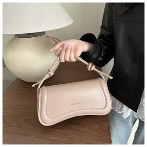 Detail of beige leather hobo bag with gold letter printing and knot strap design