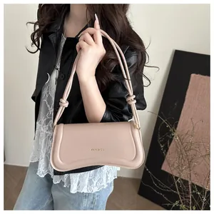 Close-up of a light pink leather underarm bag with knotted strap details and logo