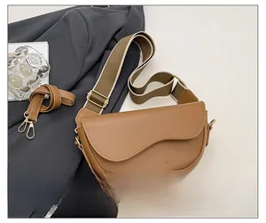 Detail view of brown saddle bag with wide woven strap and adjustable leather strap