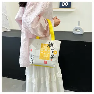 Close-up of canvas bucket bag with yellow straps and Chinese calligraphy artwork
