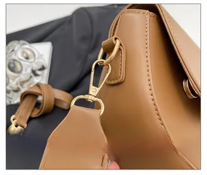 Detail view of the high-quality golden metal buckle and textured leather strap on brown bag