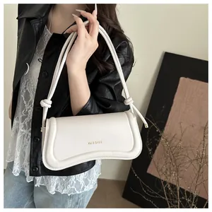 Close-up of a white leather crescent shoulder bag with knot detail and logo branding