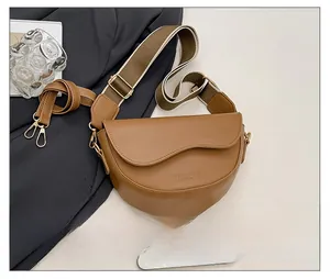 Brown leather saddle bag detail with wide strap and phone for size reference