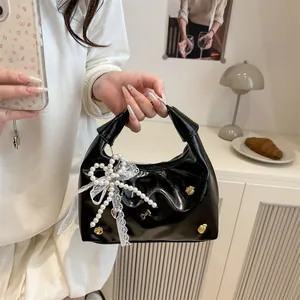 Schwarze Lackleder-Eimertasche mit Perlen-Schleife und Spitze am Modell getragen