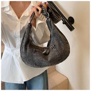 Detail of dark grey washed denim hobo bag featuring a front pocket and wide shoulder strap