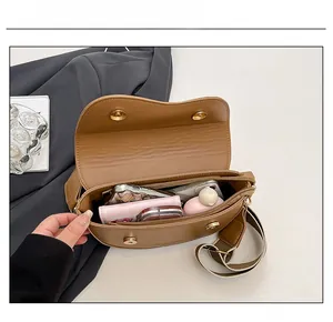 Internal capacity view of brown saddle bag showing phone, wallet and cosmetics clearly