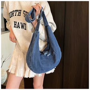 Detail of blue denim crescent crossbody bag with adjustable strap on casual outfit