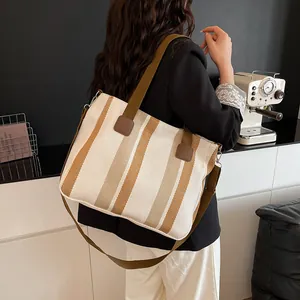 Rear view of striped canvas tote bag with adjustable strap in a cozy cafe setting