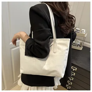 Detail of white crocodile pattern tote bag with geometric stitching on the shoulder