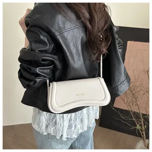 Detail of minimalist cream leather shoulder bag featuring gold XM & BAGS logo lettering