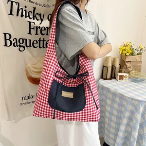 Red gingham tote bag with denim pocket and side bow detail shown in lifestyle setting