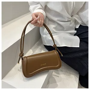 Detail of vintage brown leather handbag featuring XM & BAGS gold logo and knotted strap