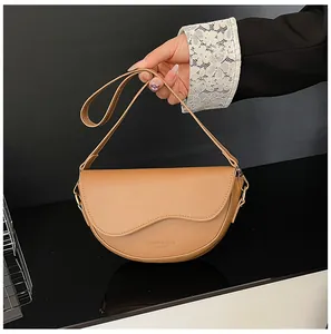 Gros plan du sac besace en cuir kaki avec bandoulière large et boucles dorées