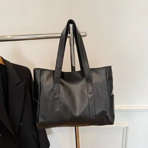 Λεπτομέρεια μαύρης δερμάτινης τσάντας tote με λεπτή υφή και πλευρική τσέπη σε κρεμάστρα