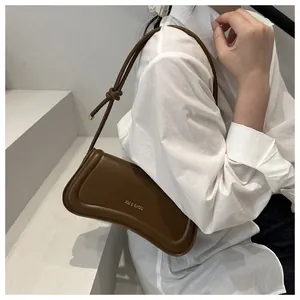 Detail of brown matte leather shoulder bag with gold XM & BAGS logo and knotted strap