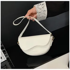 Détail du sac selle blanc en demi-lune avec rabat ondulé et boucle dorée élégante