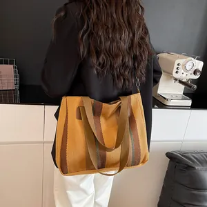 Detail of canvas tote bag with yellow stripes, detachable strap and metal hooks