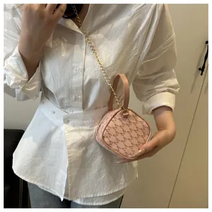 Detail view of pink crossbody bag with M-pattern and gold chain strap on a model