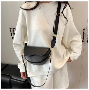 Detail of black leather saddle bag with wavy edge and adjustable wide shoulder strap