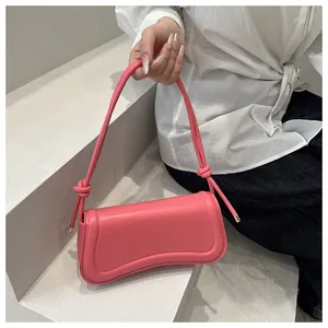 Detail showing the pink matte leather bag texture with knot strap and gold brand logo